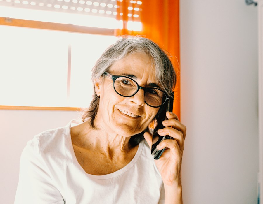 A woman in glasses smiling as she talks on her phone