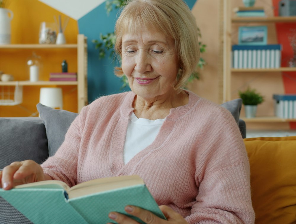 An older woman reading on her sofa at home